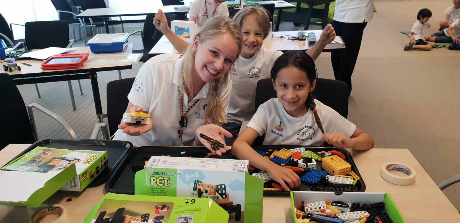 Een co-teacher bouwt samen met twee leerlingen aan een robot