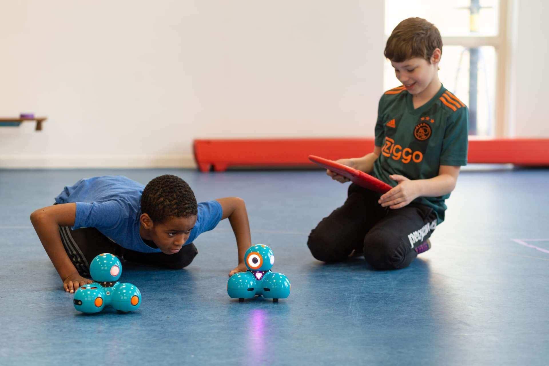 Twee leerlingen programmeren en ontdekken Dash-robots in de gymzaal