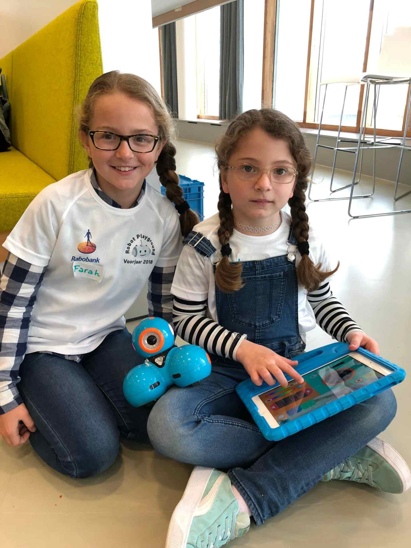 Twee leerlingen werken samen met een robot en een tablet