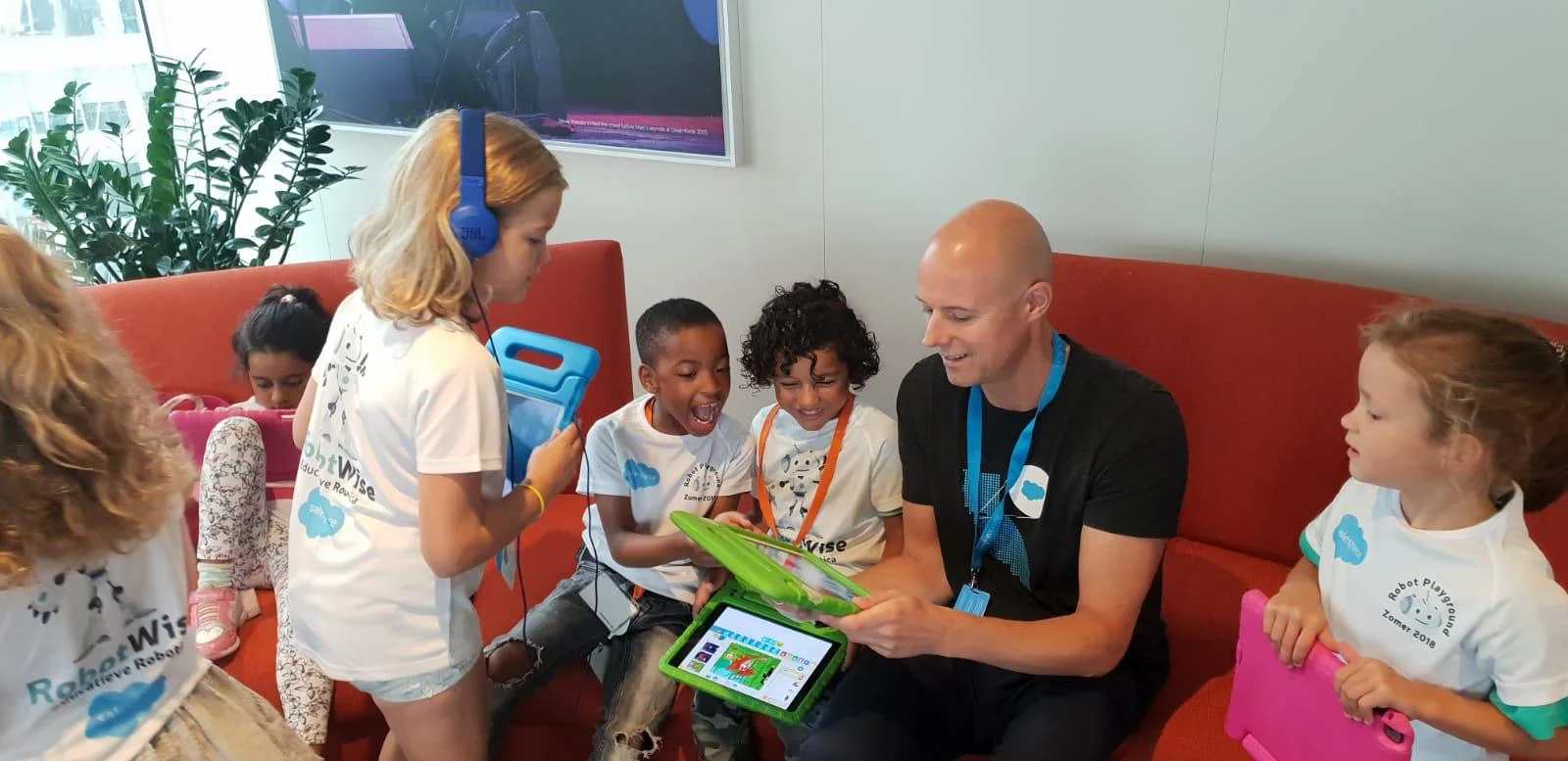 Een medewerker begeleidt als co-teacher enthousiaste leerlingen met tablets