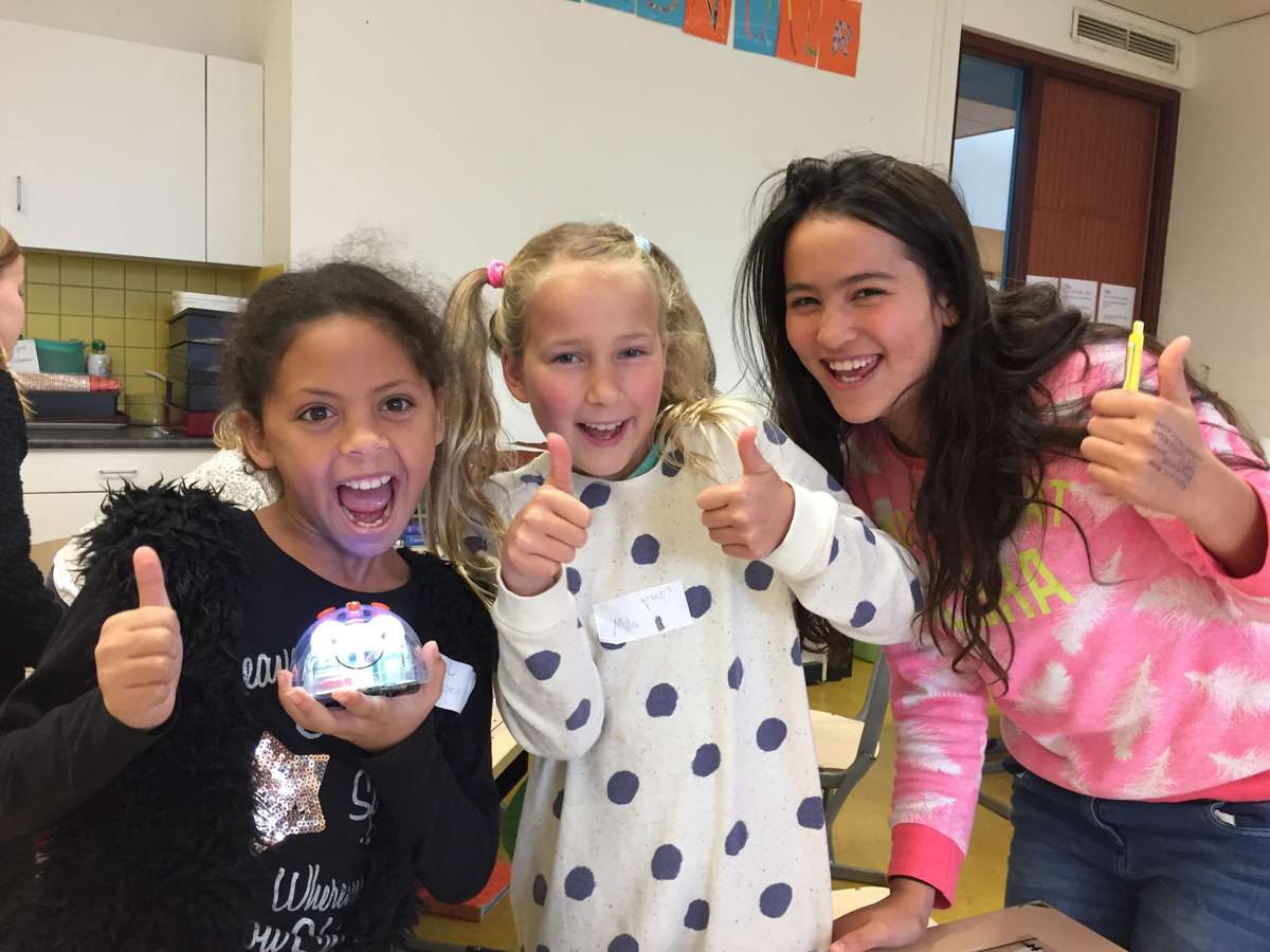Drie basisschoolleerlingen steken hun duim op tijdens een les met een educatieve robot