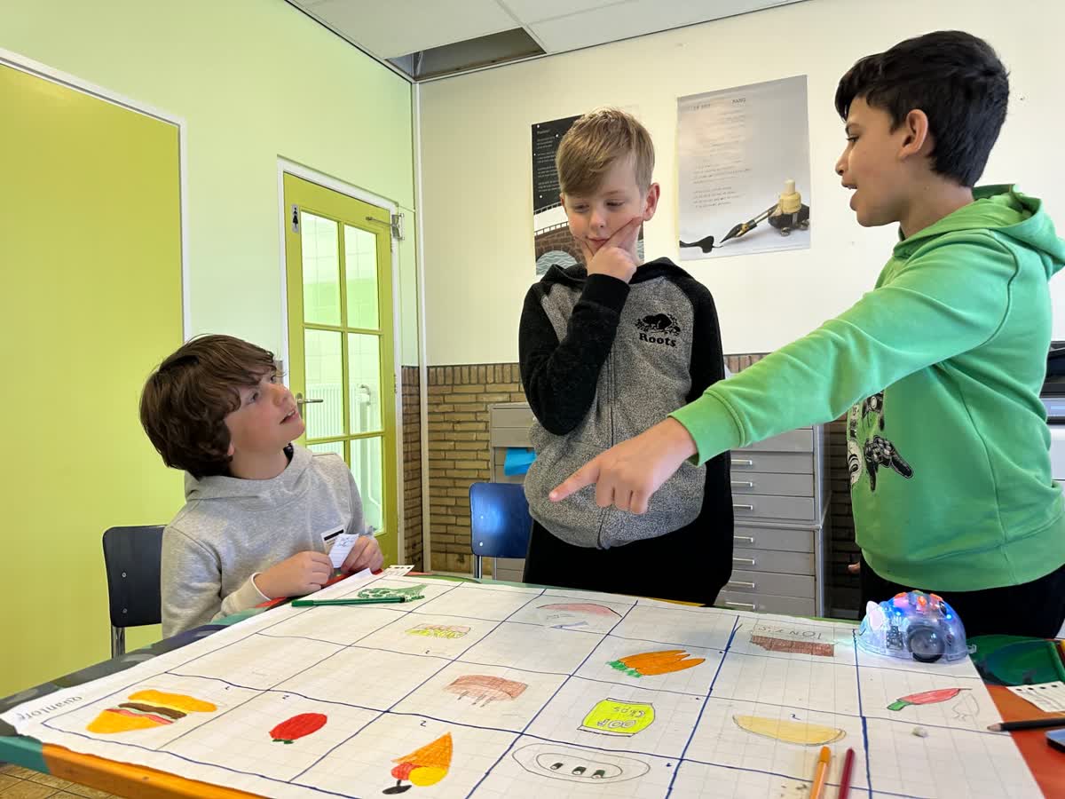 Co-teacher begeleidt leerlingen bij het programmeren van robots